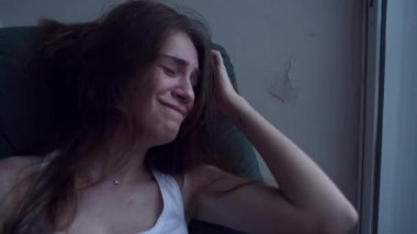 Ağır çekim Genç depresif kadın eliyle saçlarını çekerek ve sandalyede oturup ağlıyor dertte. Yalnız kadın intihar düşünceleri ile umutsuzluk içinde.