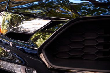 Ön farlar ve yeni bir siyah modern araba kaputuna Close-up. Lüks otomobil ayrıntıları.