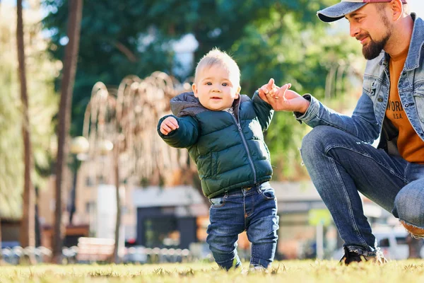 在阳光明媚的日子里 可爱的小男孩牵着父亲的手在公园里散步 父子关系 — 图库照片