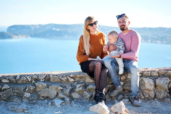 Glückliche junge Familie mit kleinem netten Jungen genießt den sonnigen Tag am Meer — Stockfoto