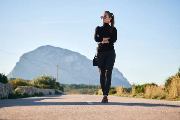 Jonge vrouw gaat op de weg tegen mooi uitzicht — Stockfoto