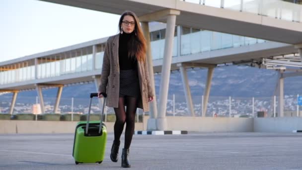 空港でハイヒールを履いた若いビジネスウーマンのスローモーション 彼女のフライトに急いでスーツケースを持つスタイリッシュな女性 — ストック動画