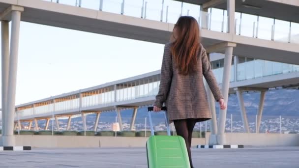 空港でハイヒールを履いた若いビジネスウーマンのバックビュー 彼女のフライトに急いでスーツケースを持つスタイリッシュな女性 スローモーション — ストック動画
