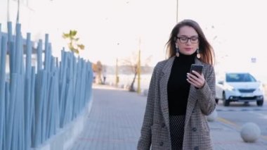 Gözlüklü genç başarılı iş kadınının cep telefonuyla birini aramasının yavaş hareketi. Şık başarılı kadın telefonda konuşuyor.