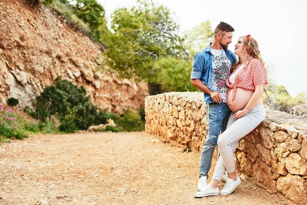 Young pregnant woman posing with her husband in a park — Stock Photo, Image