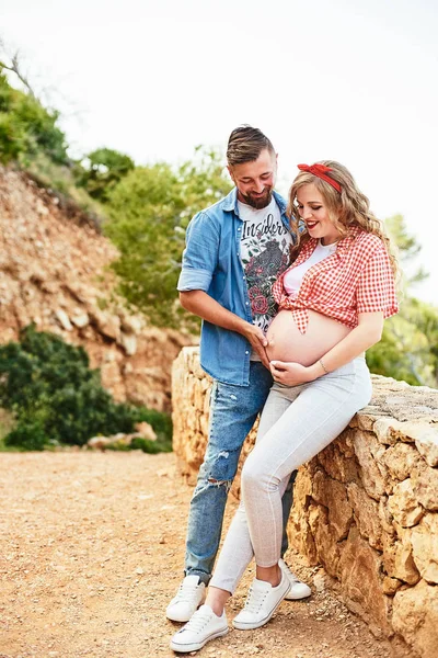 Young pregnant woman posing with her husband in a park — Stock Photo, Image