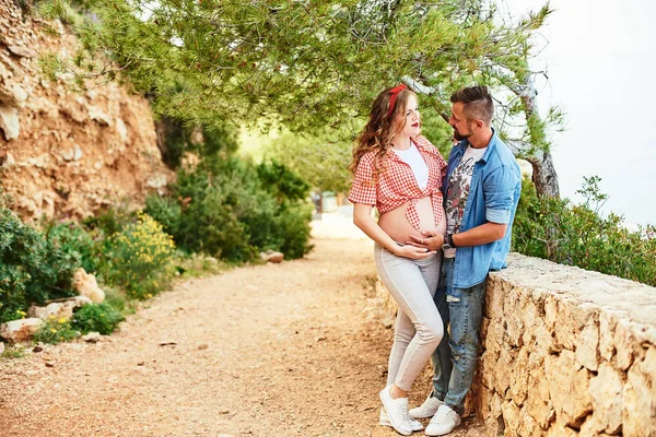 Giovane donna incinta in posa con il marito in un parco — Foto Stock