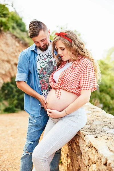 Young pregnant woman posing with her husband in a park — Stock Photo, Image