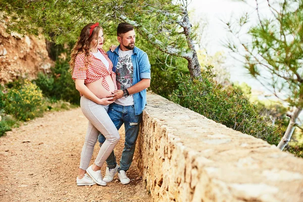 Giovane donna incinta in posa con il marito in un parco — Foto Stock