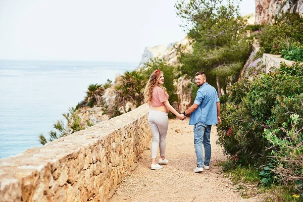 Jong zwanger vrouw poseren met haar man met zee op achtergrond — Stockfoto