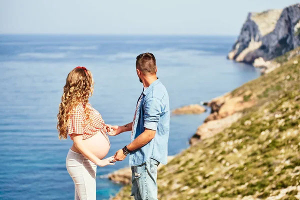 Jovem grávida caminhando com o marido contra o fundo do mar — Fotografia de Stock