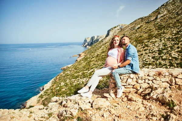 若いです妊娠中の女性とともに歩く彼女の夫と海の背景 — ストック写真