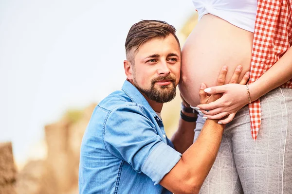 Young man listening to his pregnant wife's belly — Stock Photo, Image