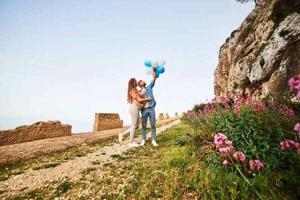 Junge gesunde Schönheit schwangere Frau mit ihrem Mann und Luftballons im Freien — Stockfoto