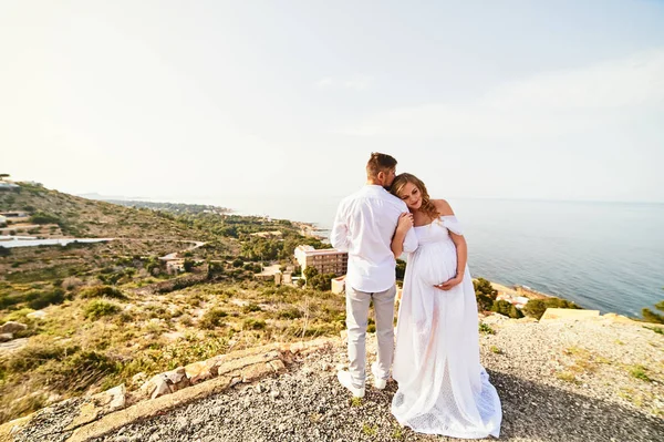 Young pregnant woman walking with her husband against sea background — 스톡 사진