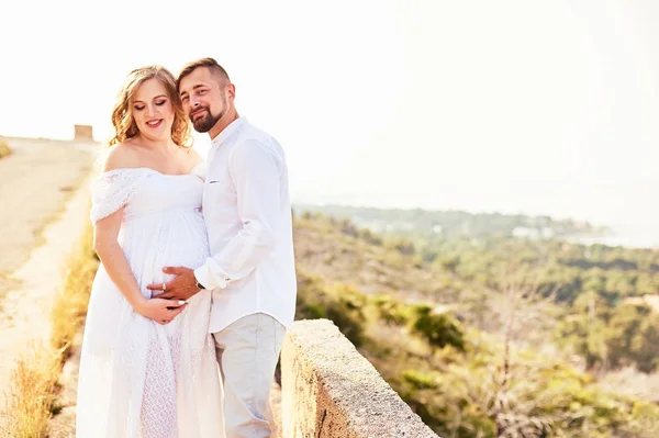 Giovane donna incinta in posa con il marito in una giornata estiva soleggiata — Foto Stock