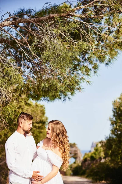 Ritratto di una giovane donna incinta in posa con il marito in una giornata estiva soleggiata — Foto Stock