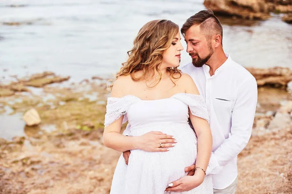 ビーチで夫とポーズをとる若い妊婦の肖像画 — ストック写真