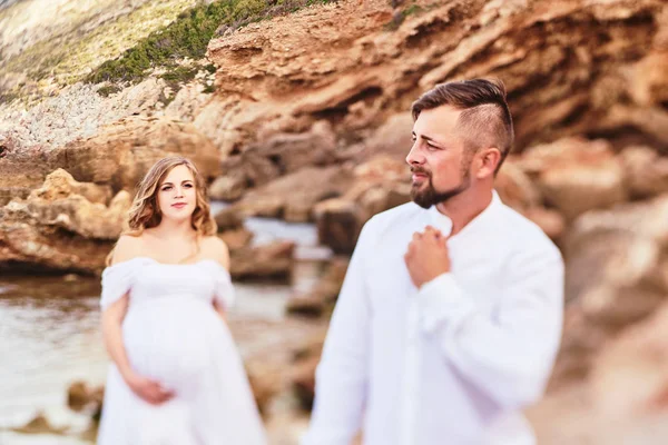 Giovane donna incinta in posa con il marito sulla spiaggia — Foto Stock