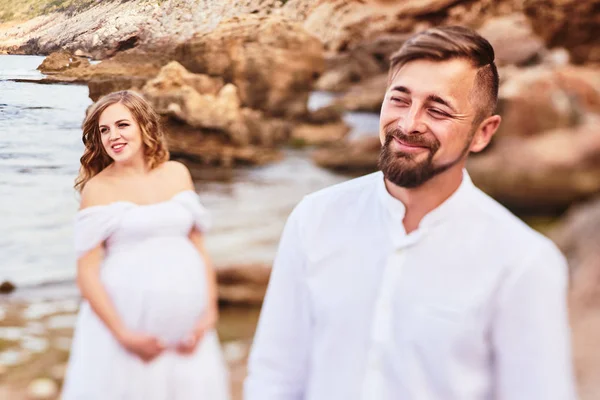 Young pregnant woman posing with her husband on the beach — Stock Photo, Image
