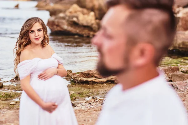 Young pregnant woman posing with her husband on the beach — Stock Photo, Image