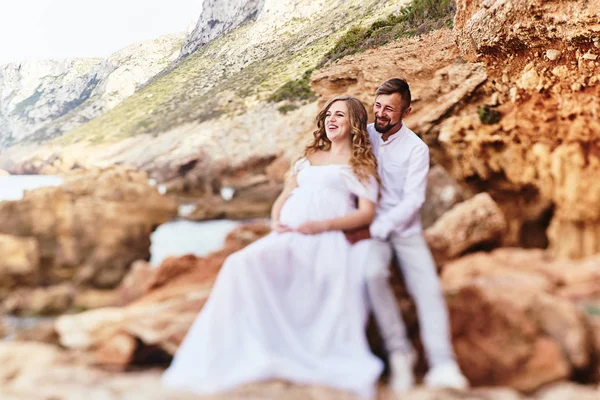 Jovem grávida posando com o marido na praia — Fotografia de Stock