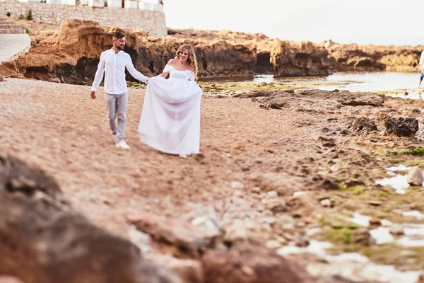 若いです妊娠中の女性歩くと彼女の夫とビーチで — ストック写真