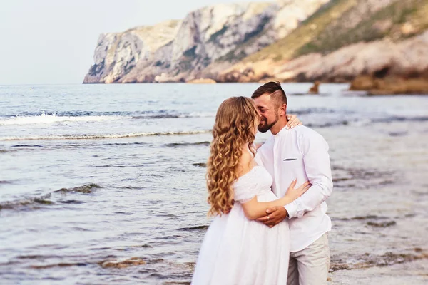 Giovane donna incinta in posa con il marito sulla spiaggia — Foto Stock