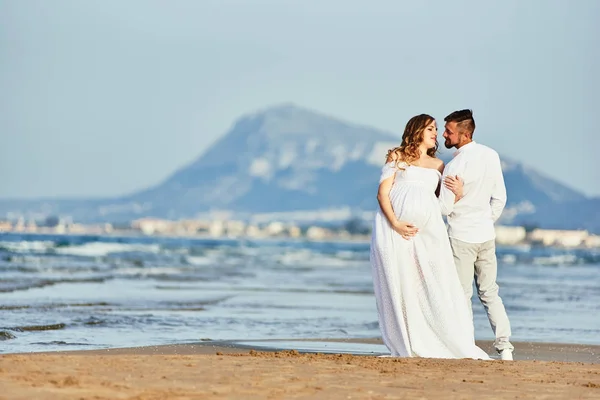 Młoda ciężarna kobieta pozowała z mężem na plaży — Zdjęcie stockowe