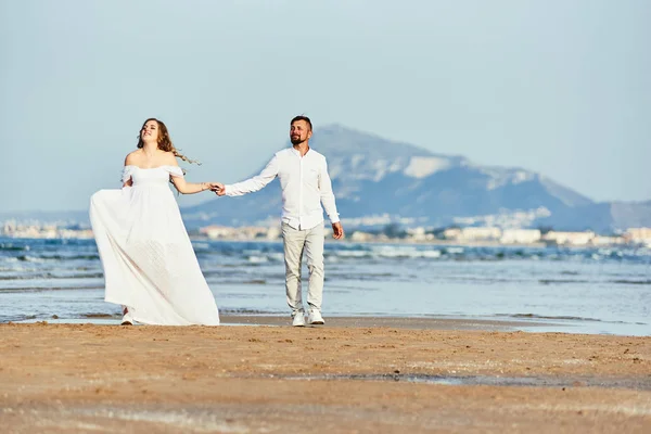 Young pregnant woman walking with her husband on the beach — 스톡 사진