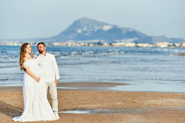 Młoda ciężarna kobieta pozowała z mężem na plaży — Zdjęcie stockowe