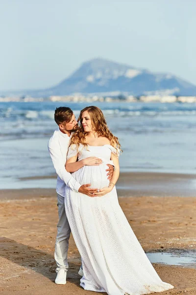 Young pregnant woman posing with her husband on the beach — 스톡 사진