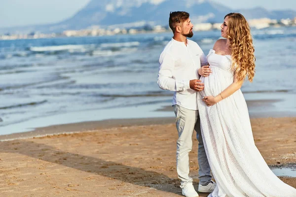 Jeune femme enceinte posant avec son mari sur la plage — Photo