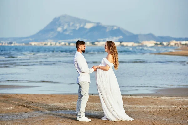 Young pregnant woman posing with her husband on the beach — 스톡 사진