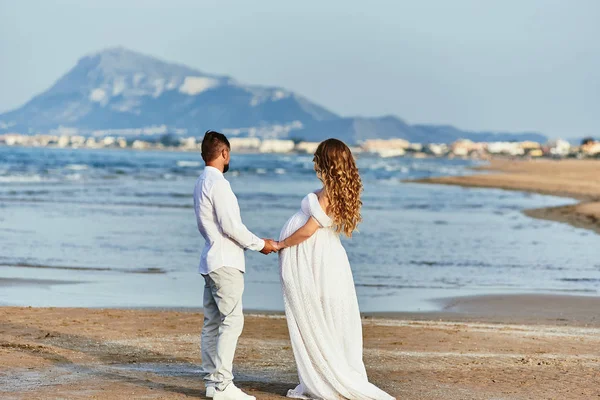 Jong zwanger vrouw poseren met haar man op het strand — Stockfoto