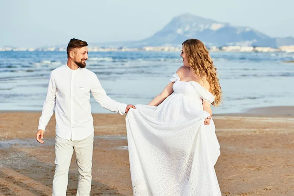 Jeune femme enceinte marchant avec son mari sur la plage — Photo