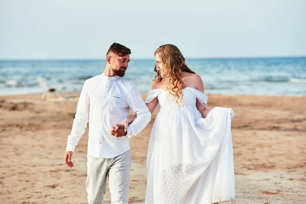 Young pregnant woman walking with her husband on the beach — 스톡 사진