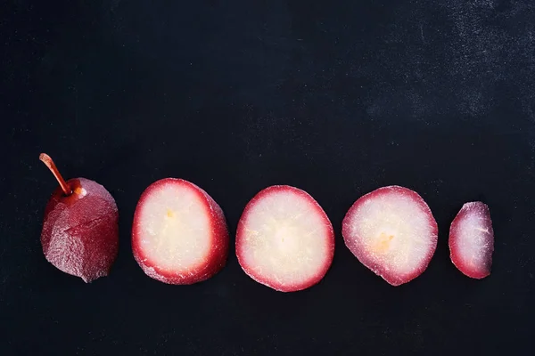 Close-up of a pear in red wine isolated on black background