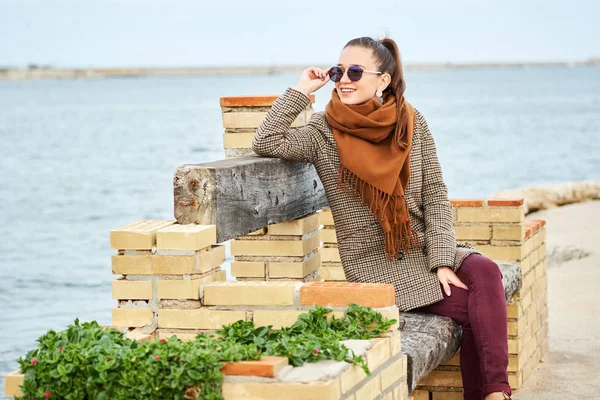 Vacker leende flicka sitter på bänken — Stockfoto