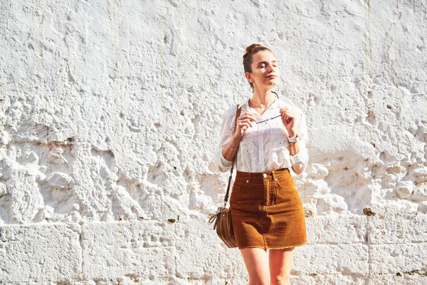 Mujer joven y elegante posando contra la vieja pared blanca —  Fotos de Stock