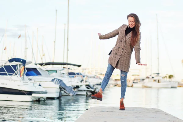 Смешная девушка в стильном пальто позирует в порту — стоковое фото