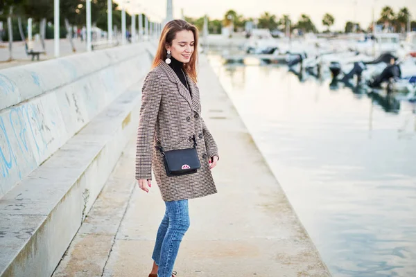 Girl in a stylish coat walking in the port