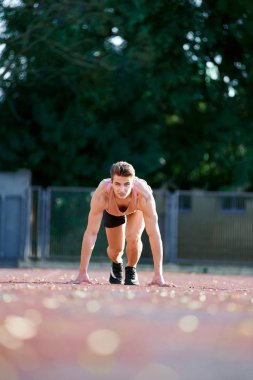Young fit and confident man in starting position ready for running