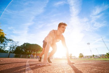 Young fit and confident man in starting position ready for running