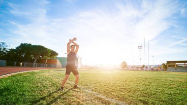 Young muscular man doing exercises on stadium
