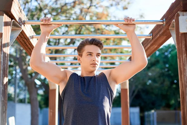 Retrato de atleta masculino treinando em barras horizontais ao ar livre — Fotografia de Stock