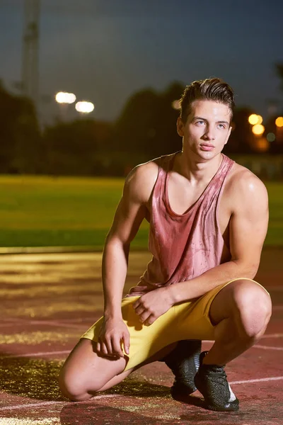 Portrait d'un jeune sportif transpirant musclé posant sur le stade — Photo
