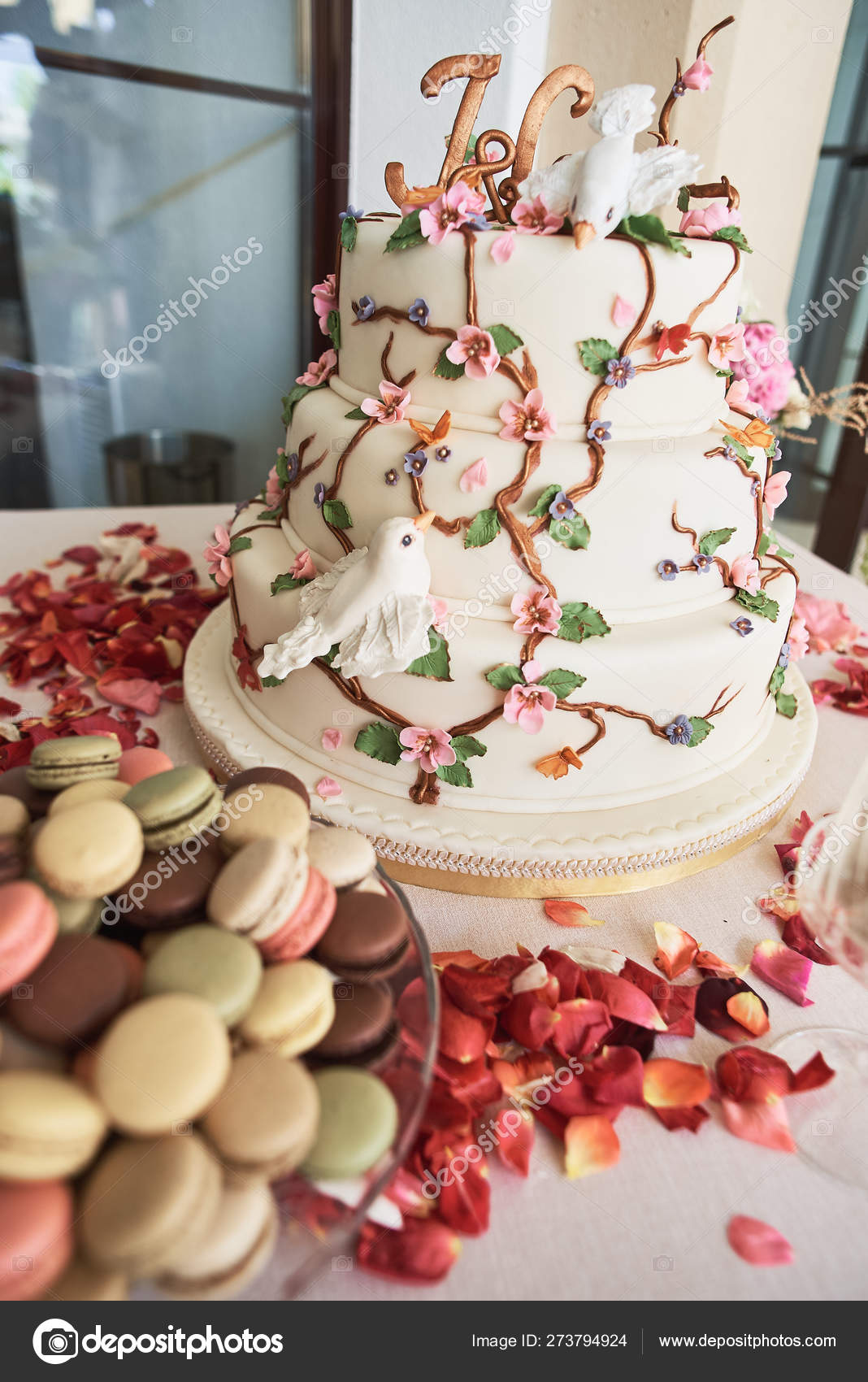 Wedding Cake With Decorative Flowers And Macarons On Candy Bar