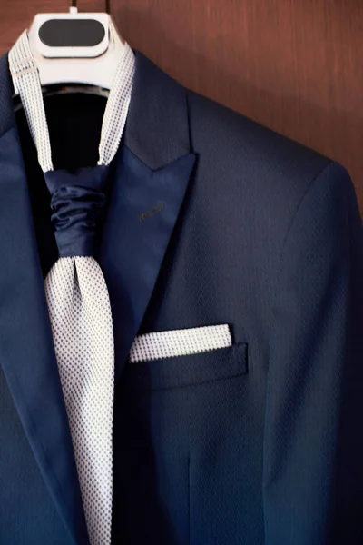 Primer plano del nuevo traje azul del novio y corbata colgando de una percha — Foto de Stock