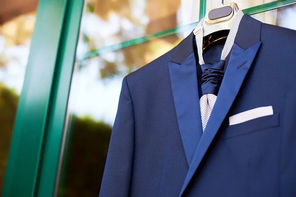 Primer plano del nuevo traje azul del novio y corbata colgando de una percha — Foto de Stock